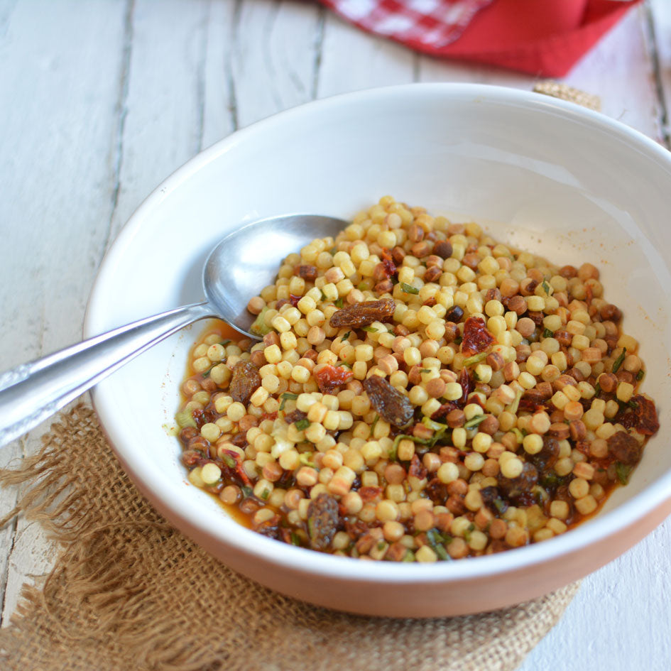 piatto di pasta fregola su tavola di legno e tovagliolo di iuta