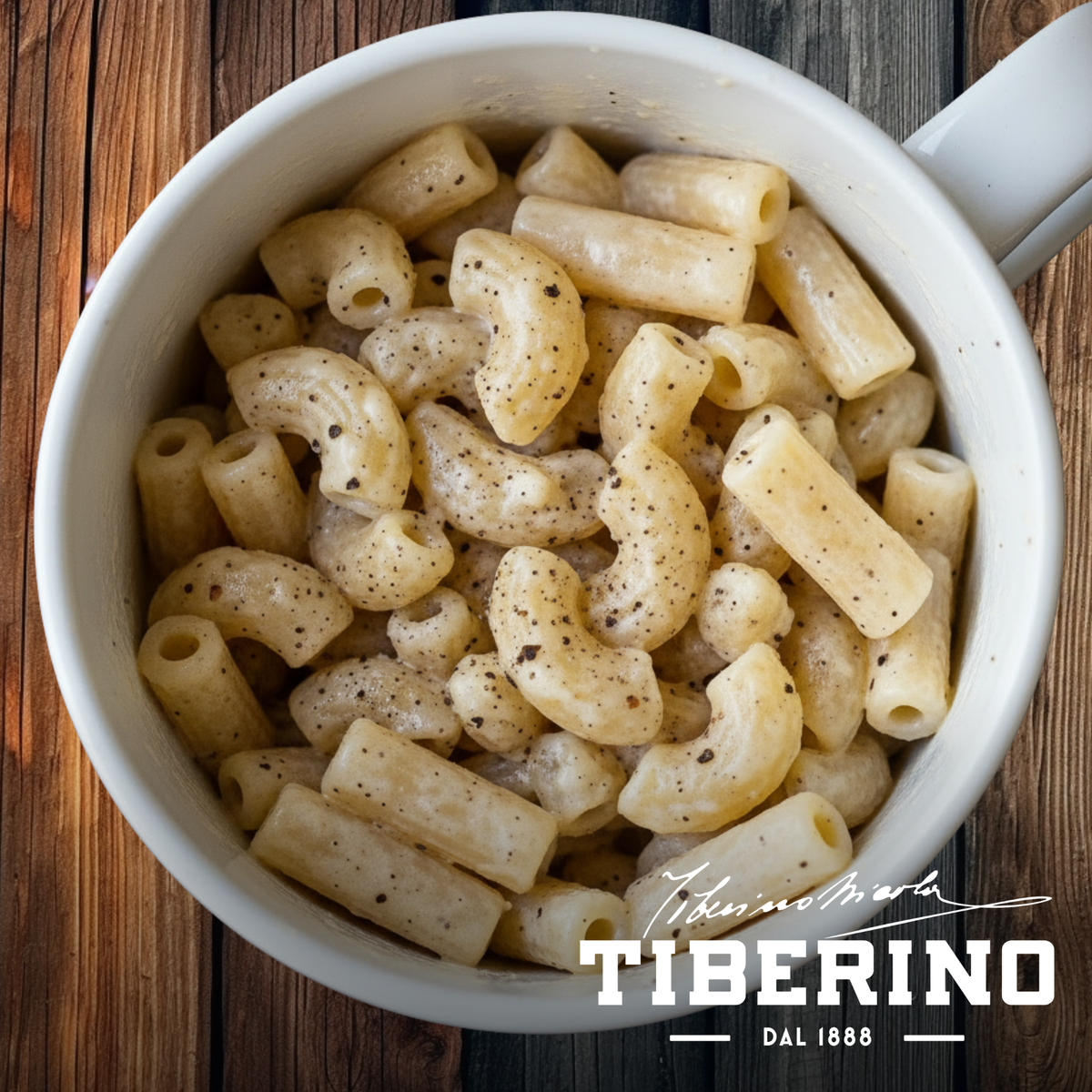 Pasta Cacio e Pepe vegana, con pepe nero macinato, servita in una tazza bianca su sfondo di legno scuro.