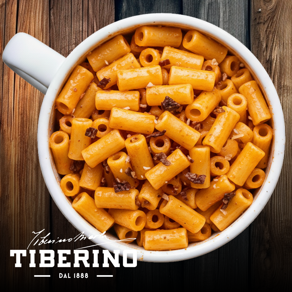 Pasta Arrabbiata vegana Tiberino 1888 in tazza bianca, con pomodoro, peperoncino e pezzi scuri, su fondo legno.